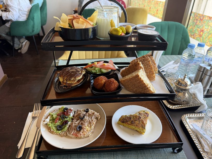 Le brunch servi sur plateau à étages : fruits frais, jus, mini-burger, croquettes, salade, cake et tortilla