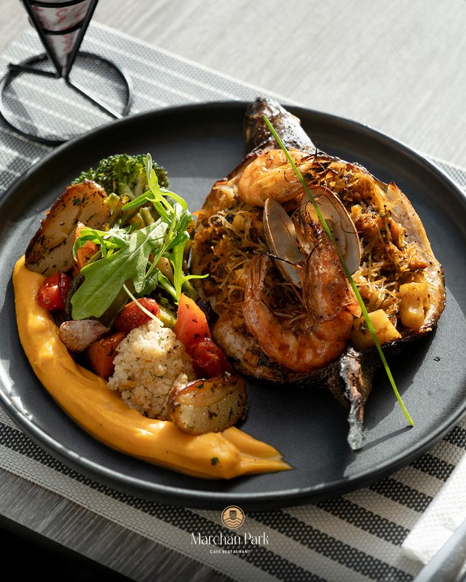 Assiette dressée : darne de poisson grillée surmontée de crevettes et d'oignons croustillants, légumes rôtis et purée de courge